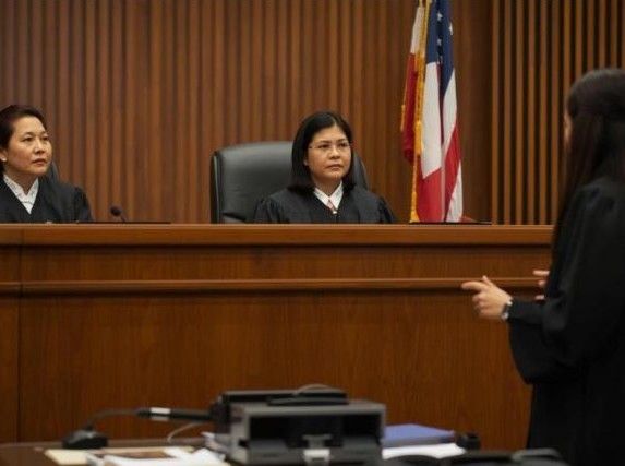 There are two judges and a lawyer in the court room.